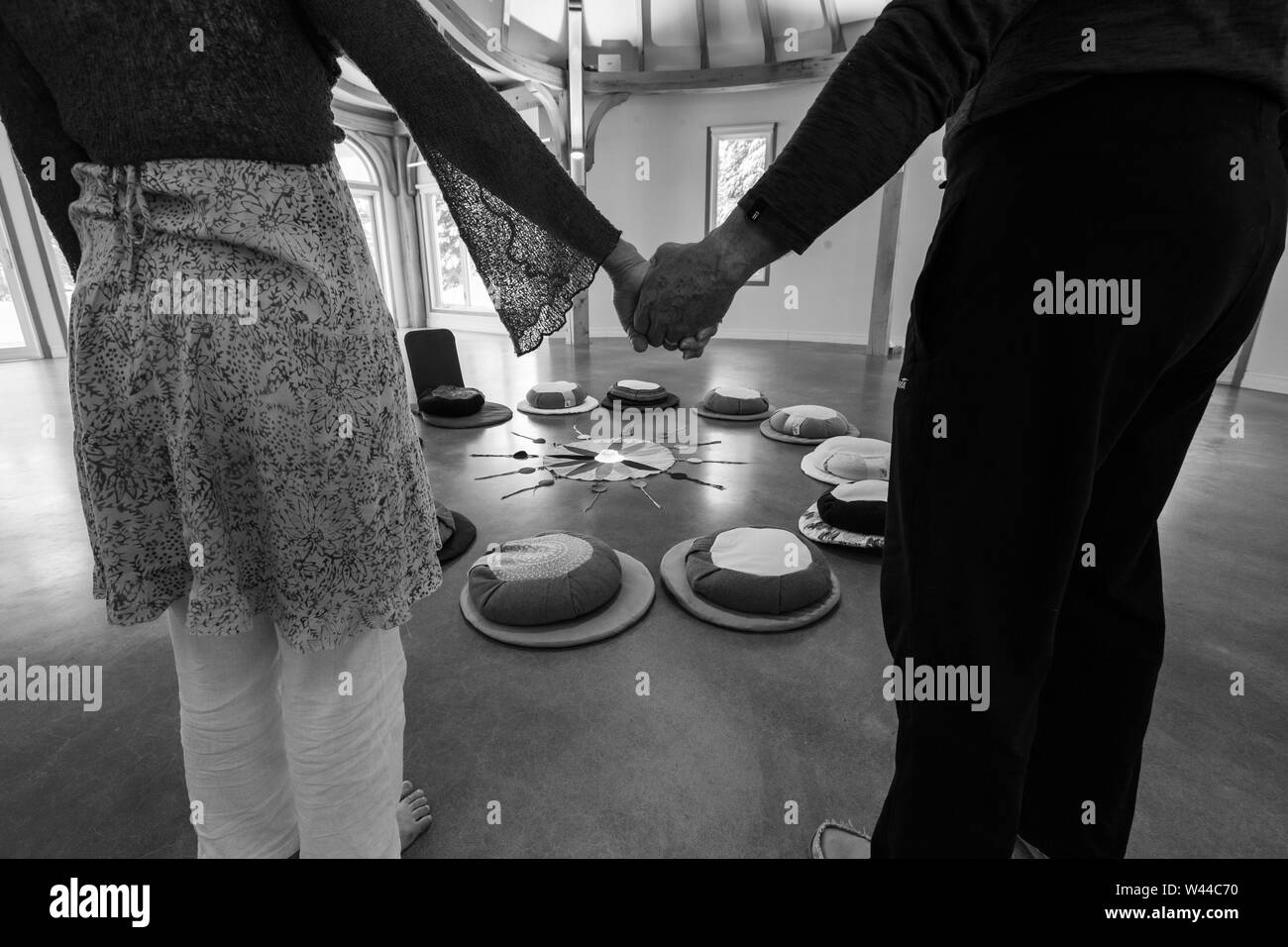 Un gros plan et vue monochrome sur deux dévots tenant la main et debout autour de la Native American roue de couleurs. Les personnes âgées méditer à l'intérieur. Banque D'Images