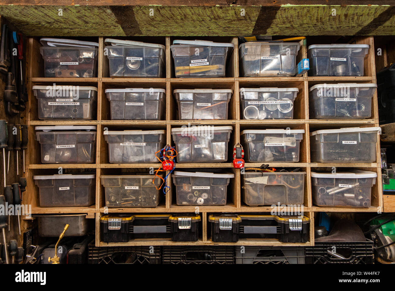 Une vue de face du matériel pour le tri des objets dans des récipients en plastique avec des étiquettes sur les étagères en bois à l'intérieur d'un atelier. Banque D'Images