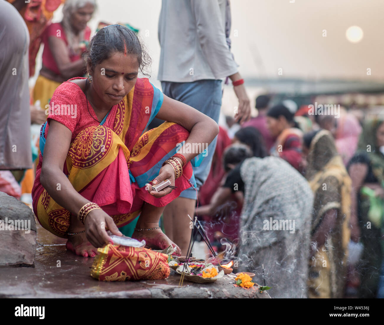 Une femme indienne préparation puja offrandes sur l'escalier vers le bas pour le Gange à Varanasi. Banque D'Images