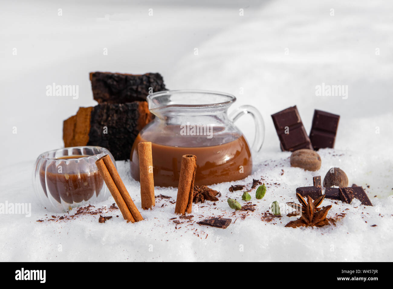 Un pichet de thé chai chaga fraîchement préparé est vu dans la neige, avec des ingrédients de la cannelle, l'anis étoilé et de chocolat noir, un verre canadien aromatiques Banque D'Images