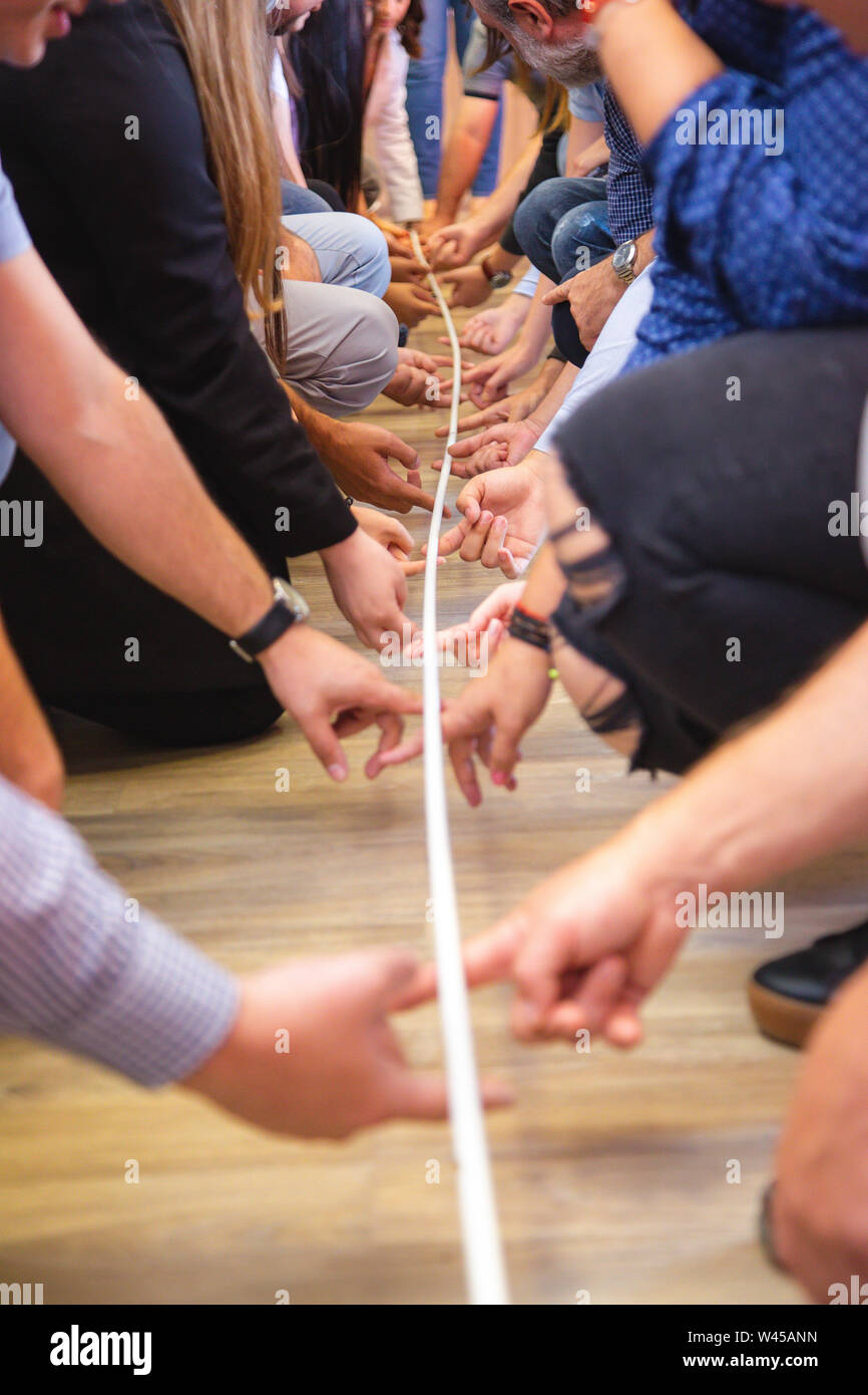 Groupe de personnes qui jouent un jeu d'équipe. L'activité de teambuilding avec stick et les mains Banque D'Images