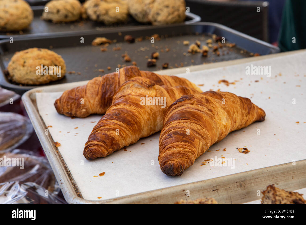 Une vue rapprochée de trois croissants fraîchement cuits sur un plateau at a market stall, flous des scones sont vus dans l'arrière-plan, des plats chauds servis à une piscine juste. Banque D'Images