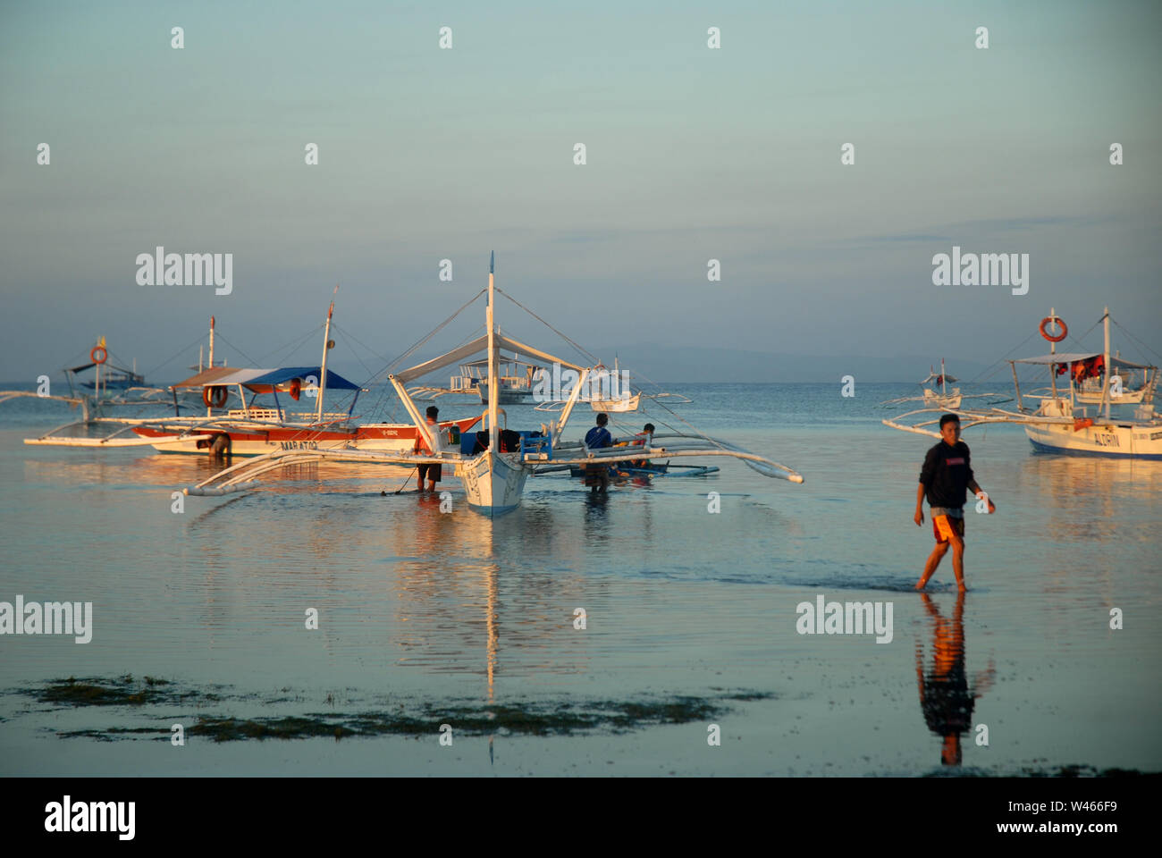 Lever du soleil sur la plage avec des bateaux banca et des pêcheurs à l'île de Panglao, Bohol, Philippines. Banque D'Images