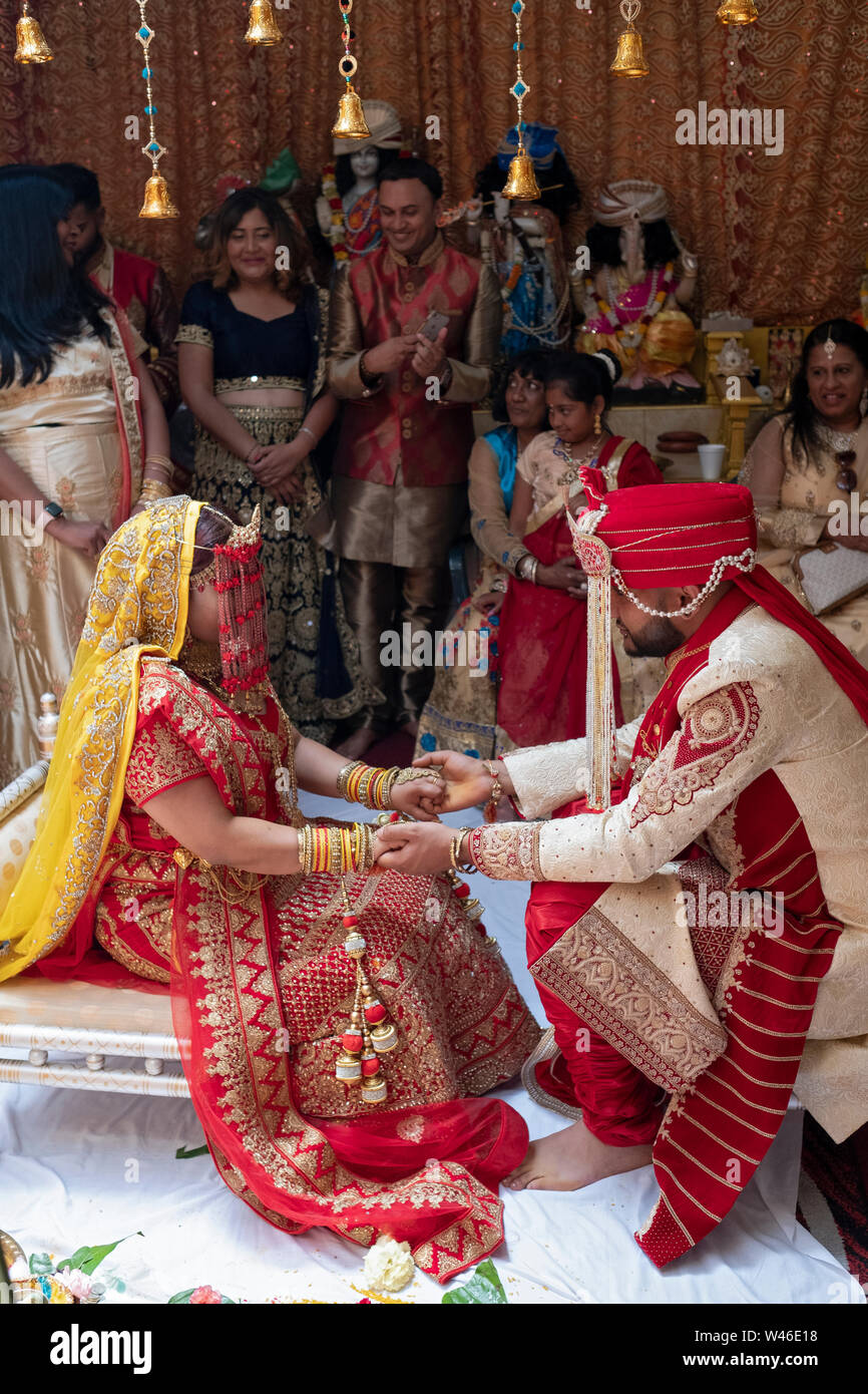 Au cours d'une cérémonie de mariage traditionnelle hindoue Shakti, la jeune mariée et se toilettent tenir la main et faire face à l'un de l'autre. Dans le Queens, New York. Banque D'Images