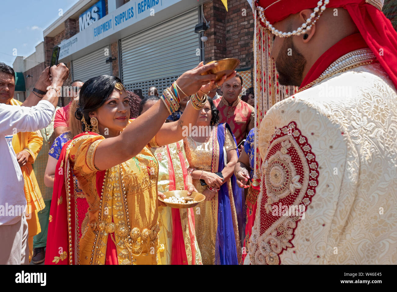 Lors d'une cérémonie de mariage traditionnelle hindoue le marié est salué et béni par la mère de la mariée avec le rituel arti en dehors du temple. Banque D'Images