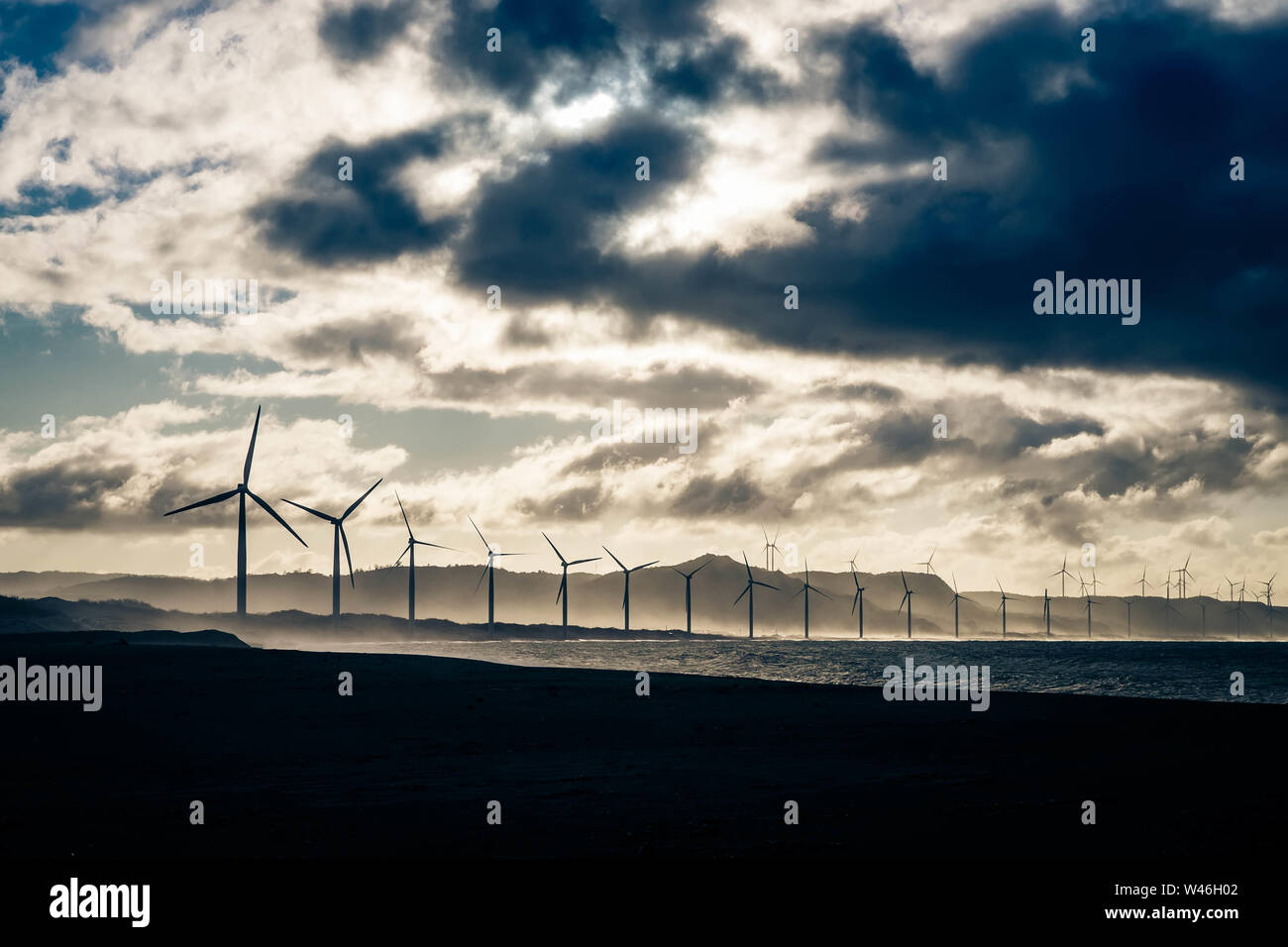 Les générateurs d'énergie éolienne en mer de silhouettes côte au coucher. La production d'énergie renouvelable de remplacement en Philippines Banque D'Images
