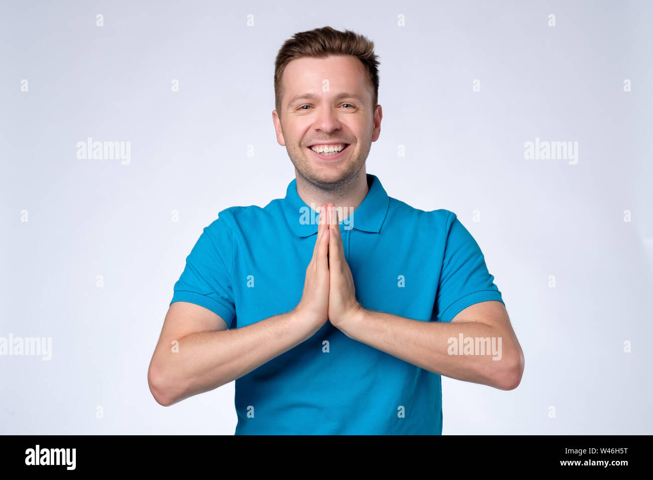 L'homme en chemise bleue holding hands in Namaste accueille ses hôtes Banque D'Images