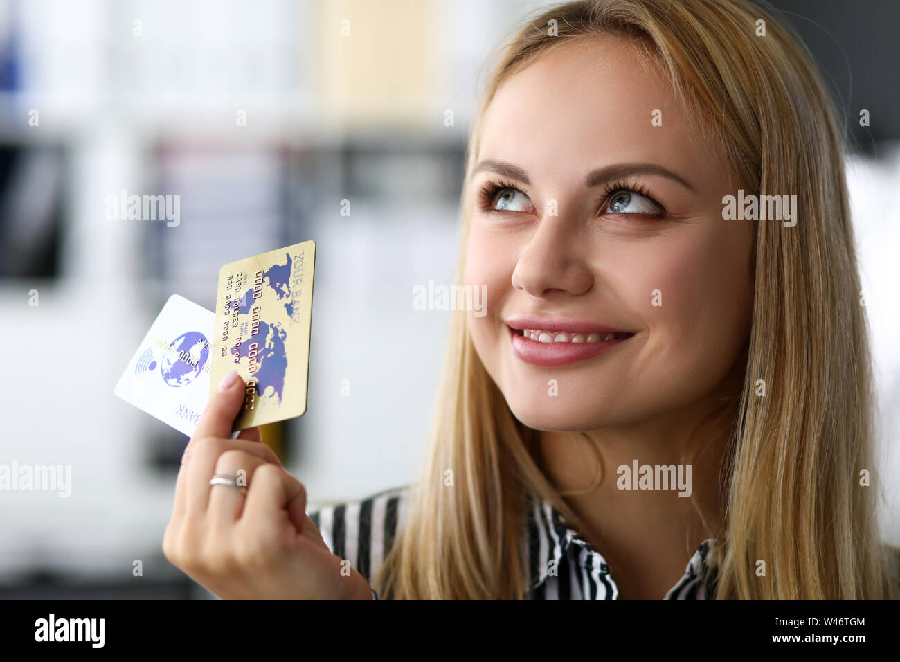 Belle blonde hot caucasian woman in office tenir deux cartes de crédit Banque D'Images