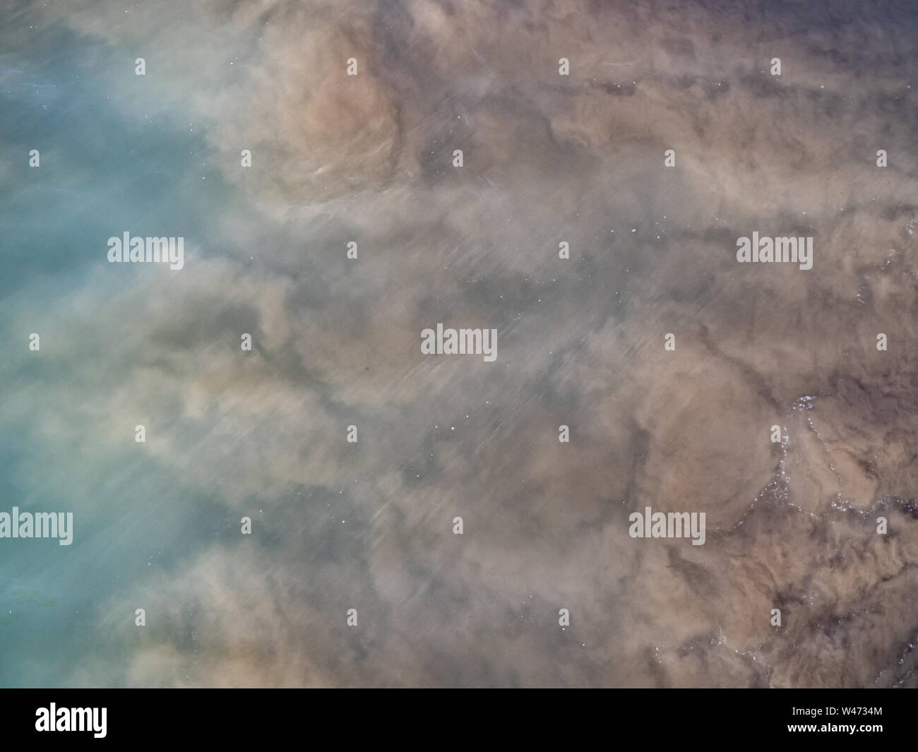 Des nuages de sable brun sous le barattage une eau bleue de l'océan Pacifique Sud, la Nouvelle Zélande Banque D'Images