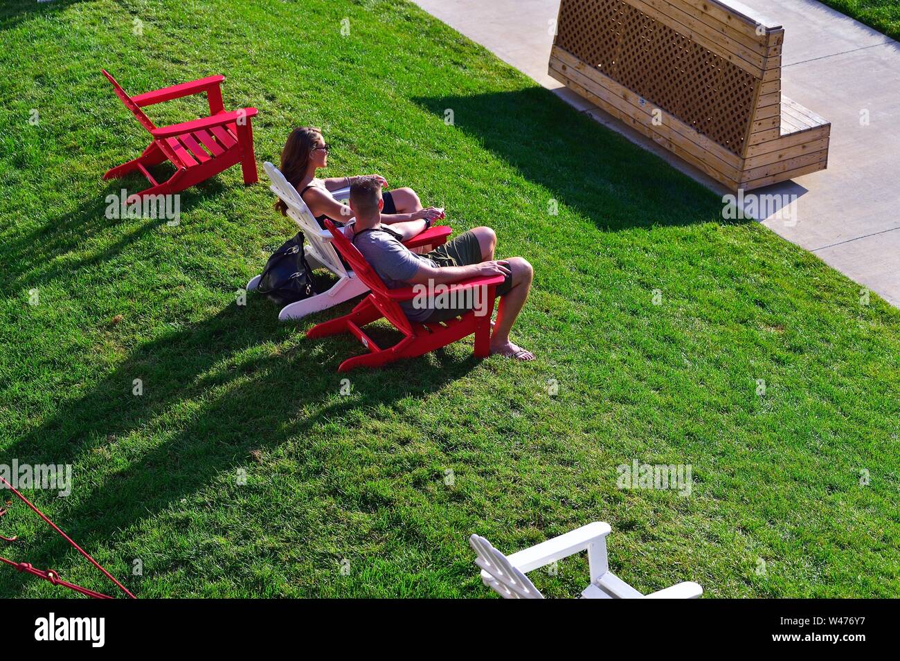 Chicago, Illinois, USA. Couple se prélasser dans les chaises en début de soirée le long de la Chicago Riverwalk, un niveau de l'eau promenade le long de la rivière Chicago. Banque D'Images