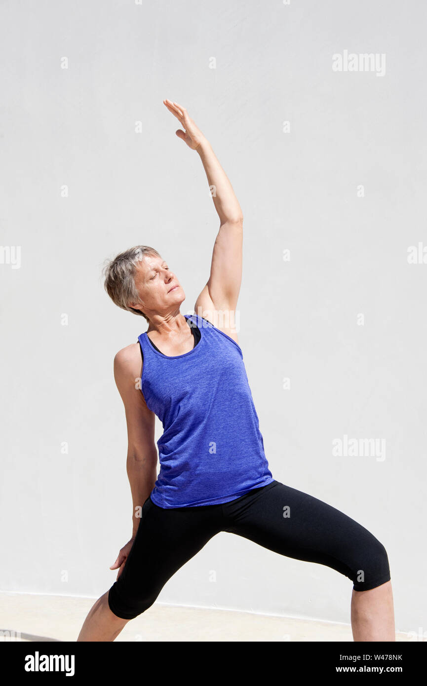 Practing mature woman gentle restorative yoga pose photographiés dans un fond blanc. Banque D'Images