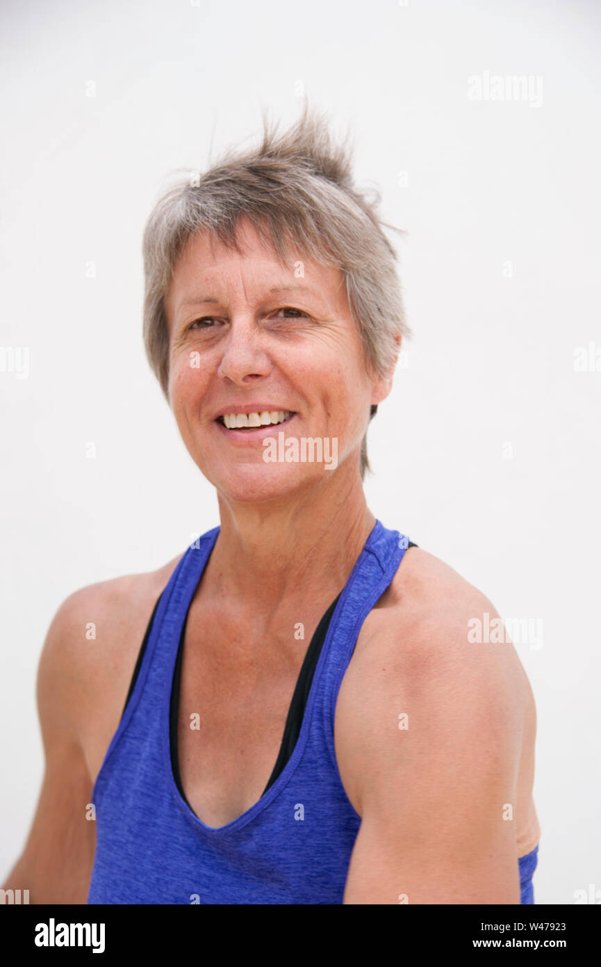 Senior mature woman practicing yoga réparatrice douce pose smiling portrait photographié sur un fond blanc. Banque D'Images