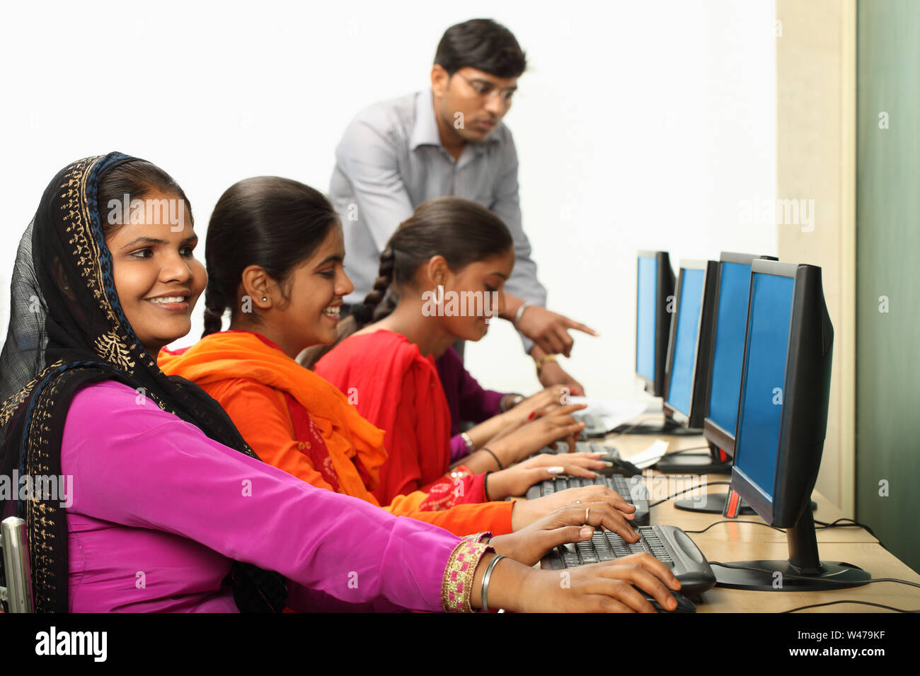 Les femmes utilisant des ordinateurs avec l'aide des enseignants Banque D'Images