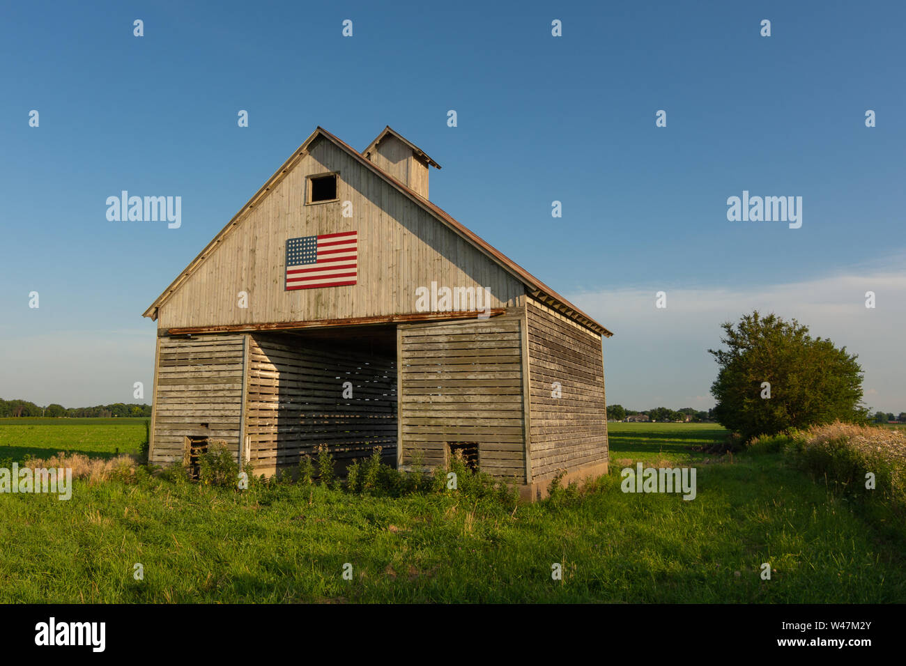 Ancienne grange en bois dans le Midwest avec le drapeau américain à la lumière de l'après-midi. LaSalle County, Illinois, États-Unis Banque D'Images