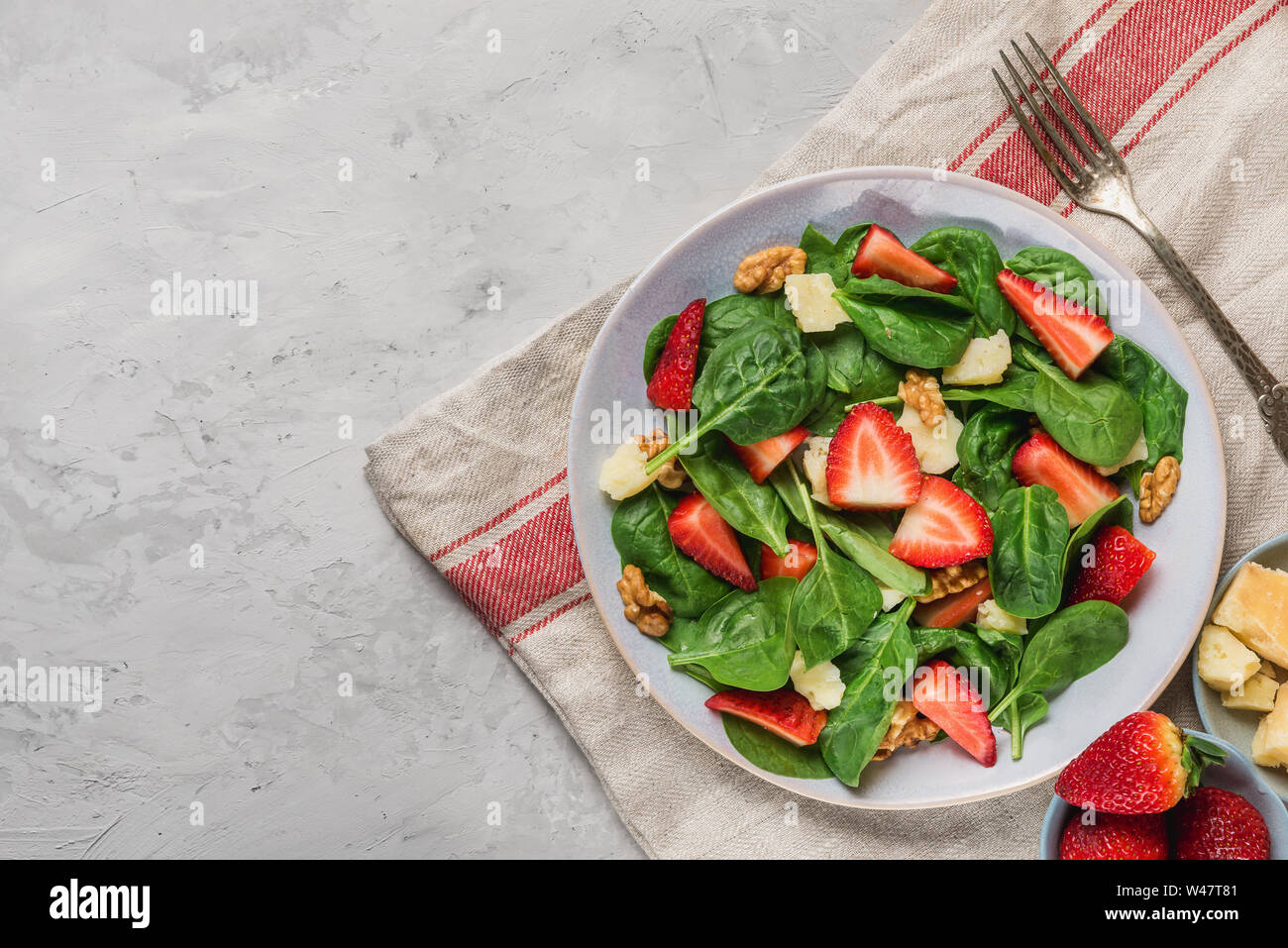 Salade d'été avec les feuilles d'épinards, fraises, fromage parmesan, l'huile d'olive et noix. Le régime alimentaire sain keto. Vue de dessus Banque D'Images