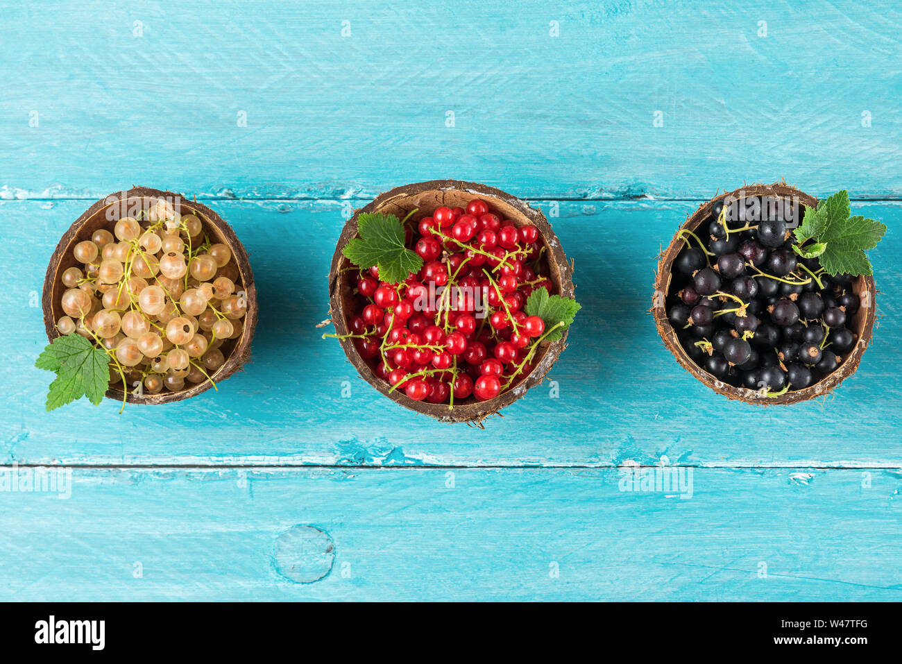 Mélange de petits fruits Groseillier noir, rouge et blanc dans un bols sur fond de bois bleu. été food concept. Télévision. Vue de dessus Banque D'Images