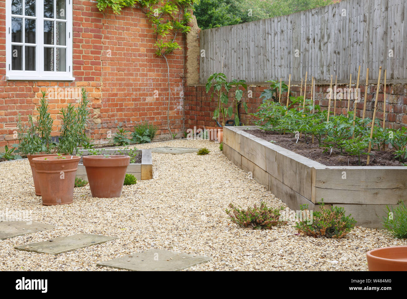 Jardin avec des pots en terre cuite, chêne sleeper lits surélevés et de gravier Banque D'Images