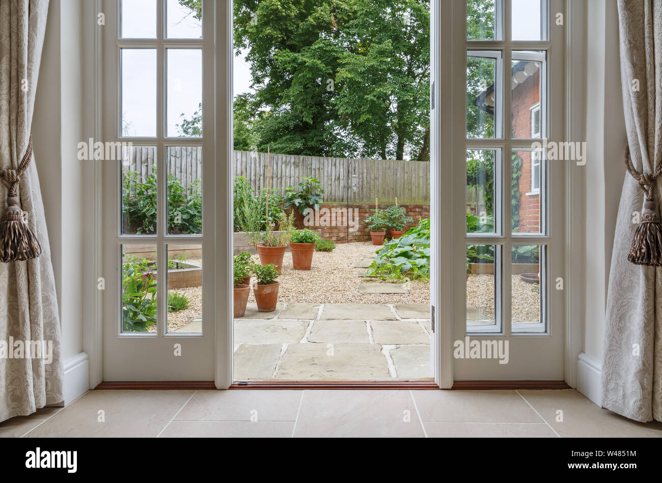 Vue sur le jardin de l'intérieur chambre avec portes françaises menant à la cour-jardin de cuisine Banque D'Images