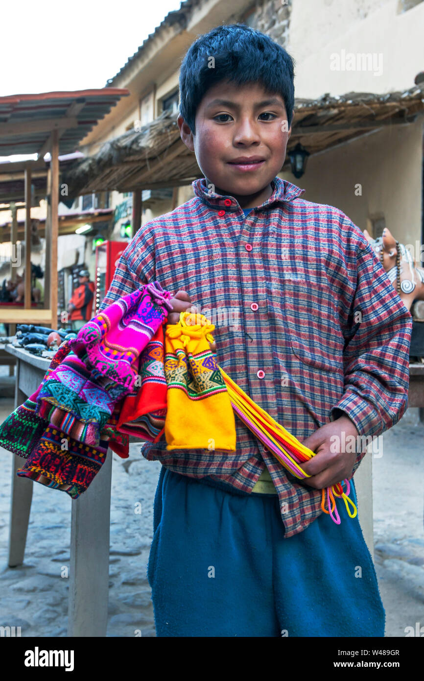 Un jeune vendeur textile vente dans le marché d'Ollantaytambo qui siège dans la Vallée Sacrée des Incas au Pérou. Banque D'Images