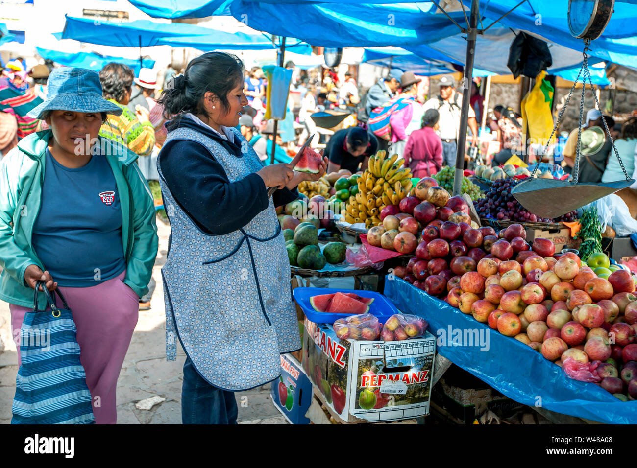 PISAC, PÉROU - 30 avril 2012 : Un vendeur de fruits un morceau de pastèque tranches sur le marché de pisac dans la Vallée Sacrée des Incas au Pérou. Banque D'Images