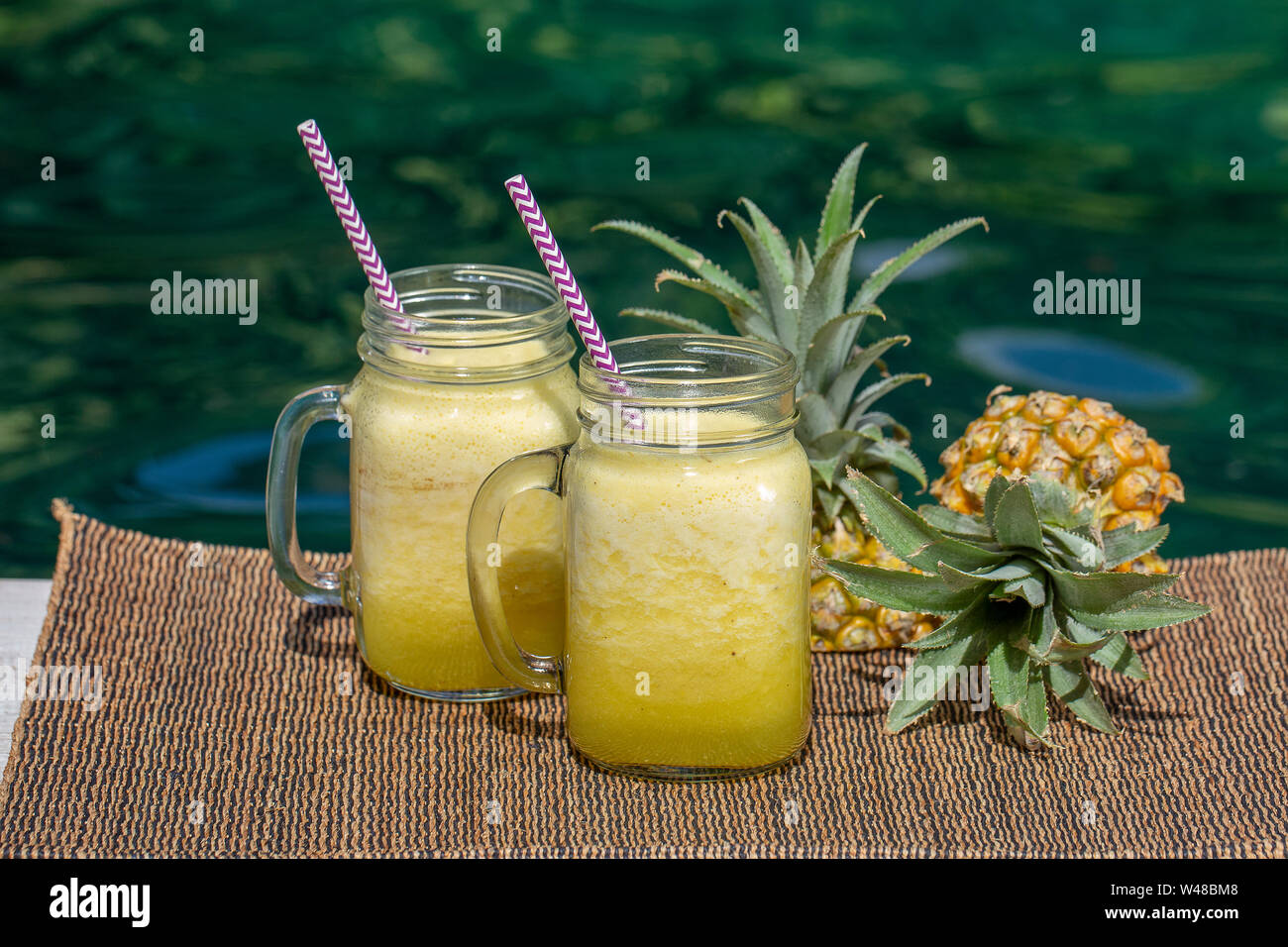 Smoothie mangue et d'ananas maison faite avec du lait de coco en deux mug verre proche piscine, Close up. Island Bali, Indonésie. Tropica rafraîchissante Banque D'Images