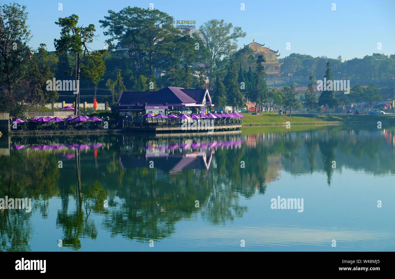 Paysage romantique de violet Lakeside Café avec parasol groupe reflètent sur l'eau du lac de Xuan Huong, Da Lat city centre à matin Banque D'Images