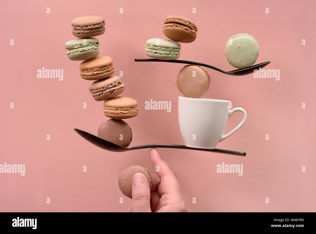 Concept d'équilibre télévision jeter sur papier couleur corail. L'équilibre entre tasse de café et macarons sur un doigt Banque D'Images