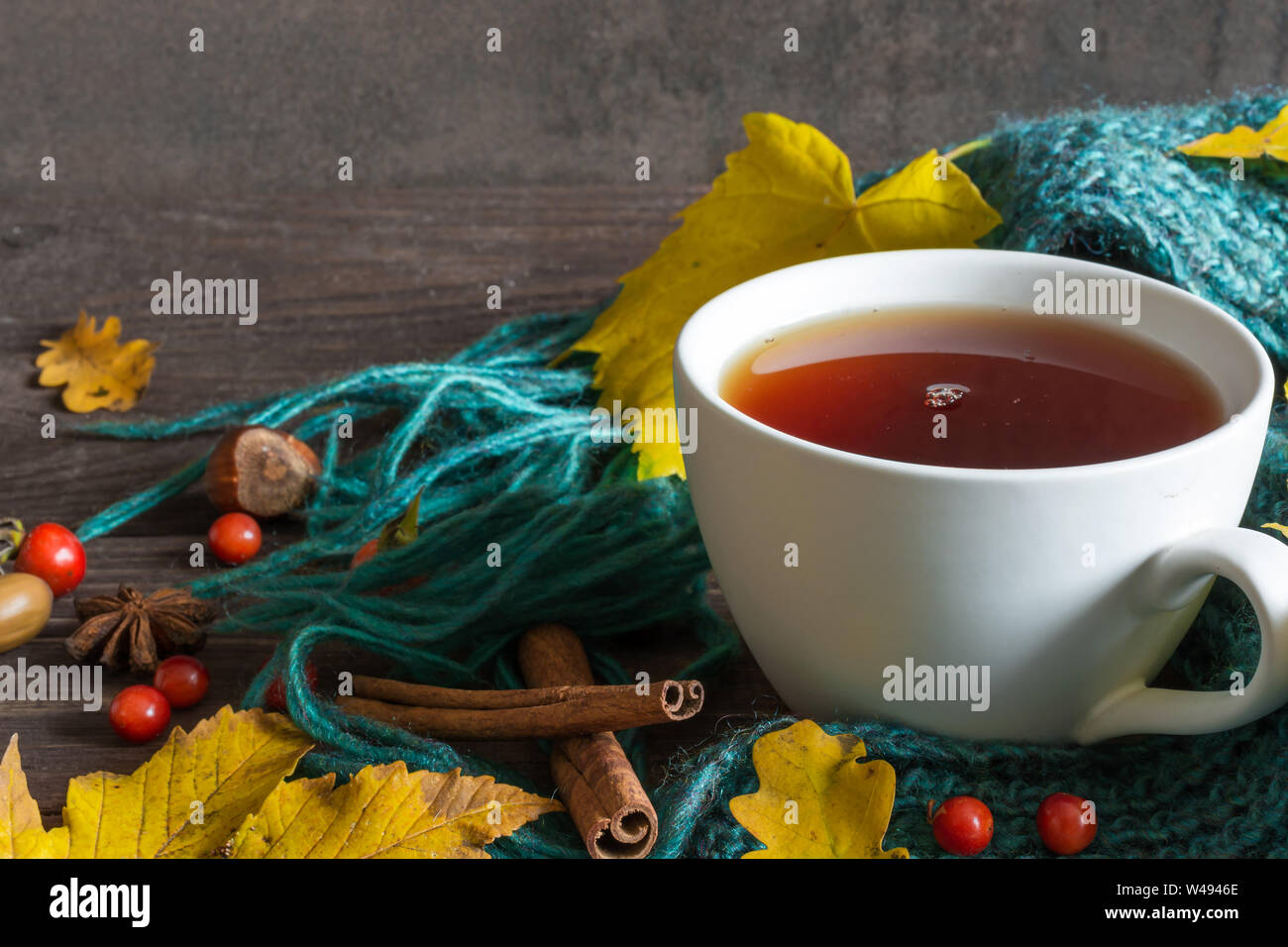 Automne fond avec des feuilles sèches, écharpe, tasse de thé avec des épices sur la table en bois. close up Banque D'Images