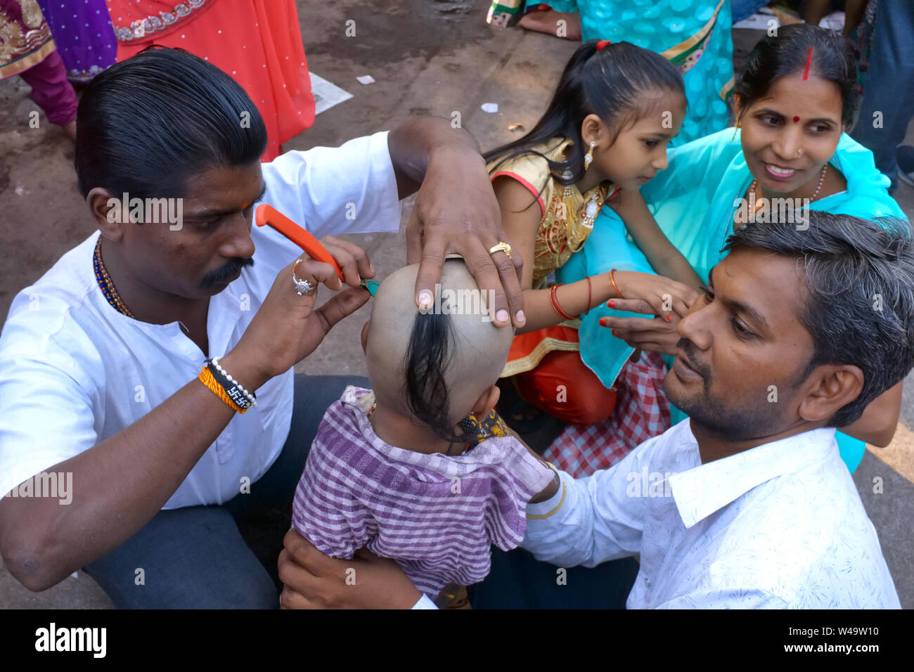 Selon la coutume hindoue, un jeune garçon reçoit sa première coupe de cheveux après une visite familiale à un temple hindou ; Mumbai, Inde Banque D'Images