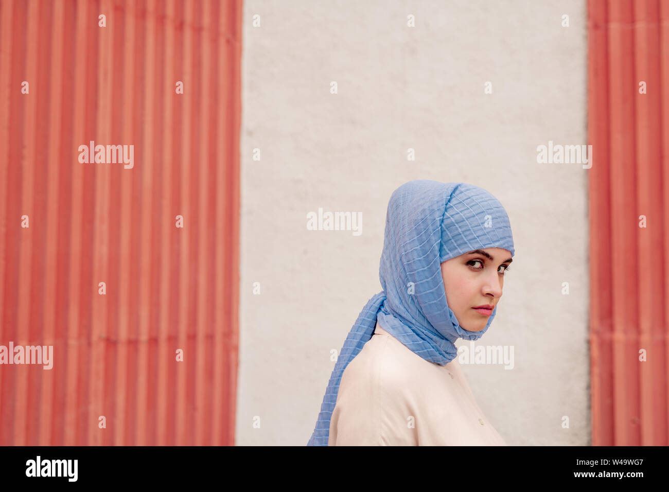 Jeune femme musulmane en bleu hijab debout près de mur du bâtiment Banque D'Images