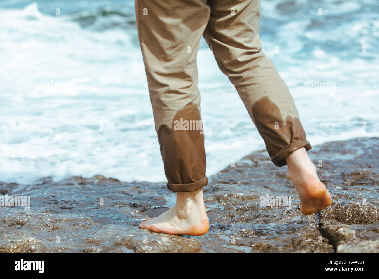 L'homme mouillé les jambes de pantalons à pied par l'eau de mer plage sable  profitant de vacances d'été Photo Stock - Alamy