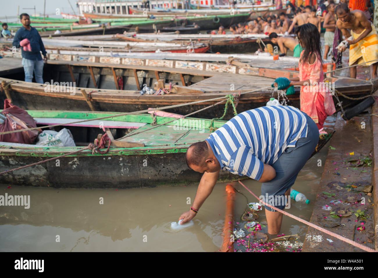 Un homme qui l'eau du fleuve saint Ganges à Varanasi. Banque D'Images