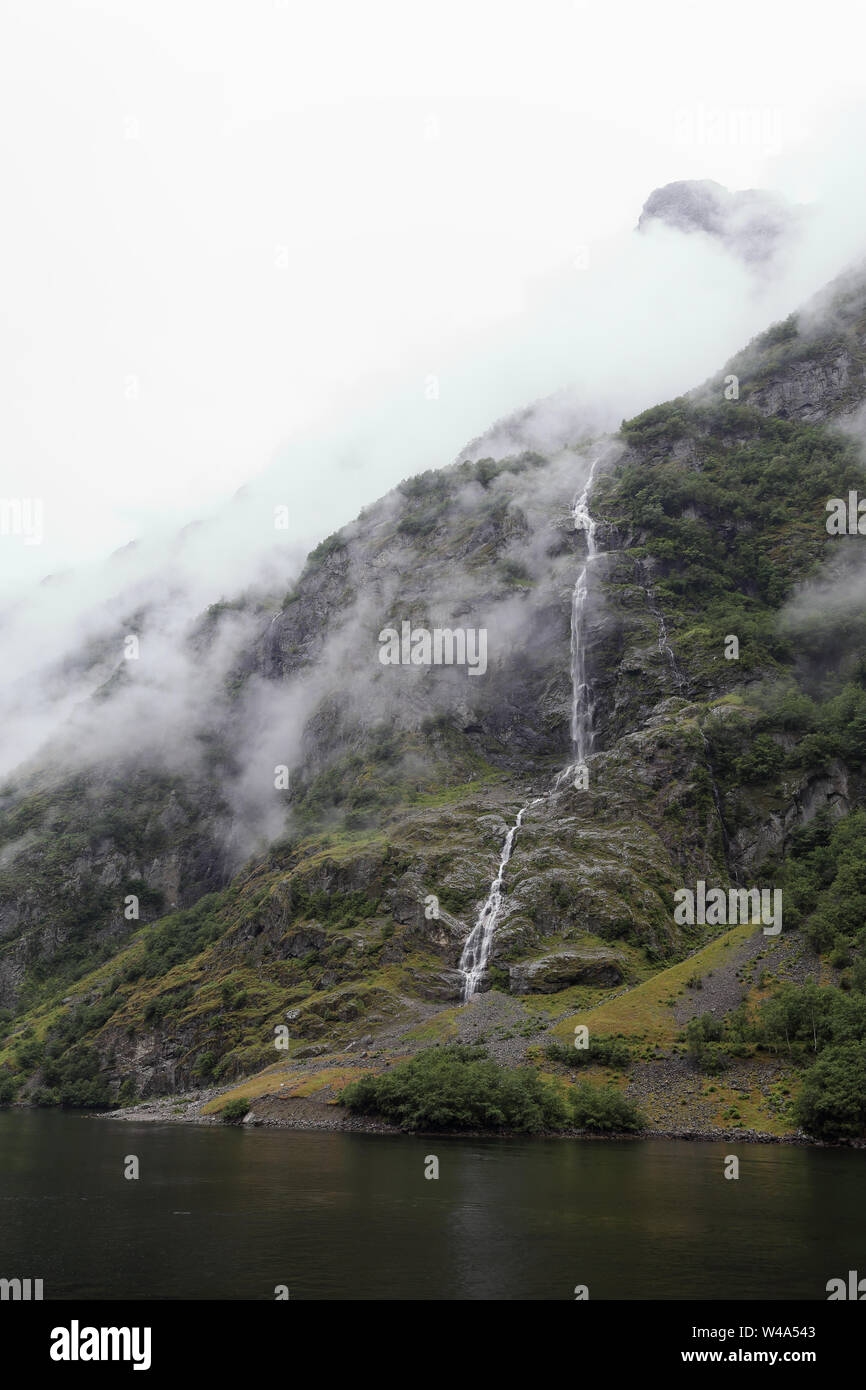 Petit passage de l'eau descendant la pente d'un fjord en Norvège dans un jour brumeux Banque D'Images