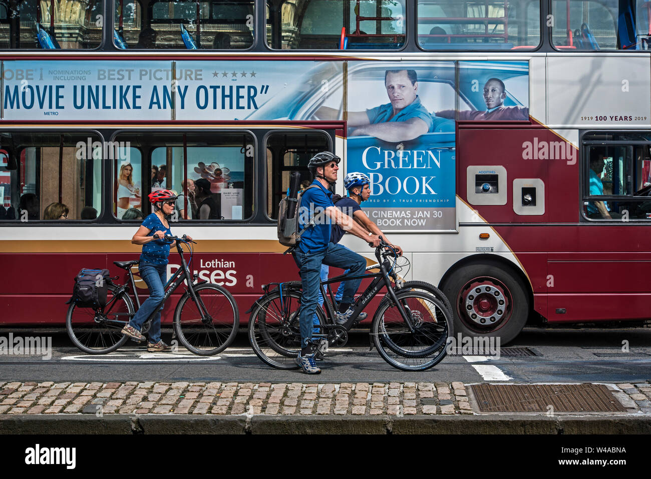 Trois coureurs attendent les lumières de modifier à côté d'un bus Lothian sur Princes Street, Édimbourg, Écosse, Royaume-Uni. Banque D'Images