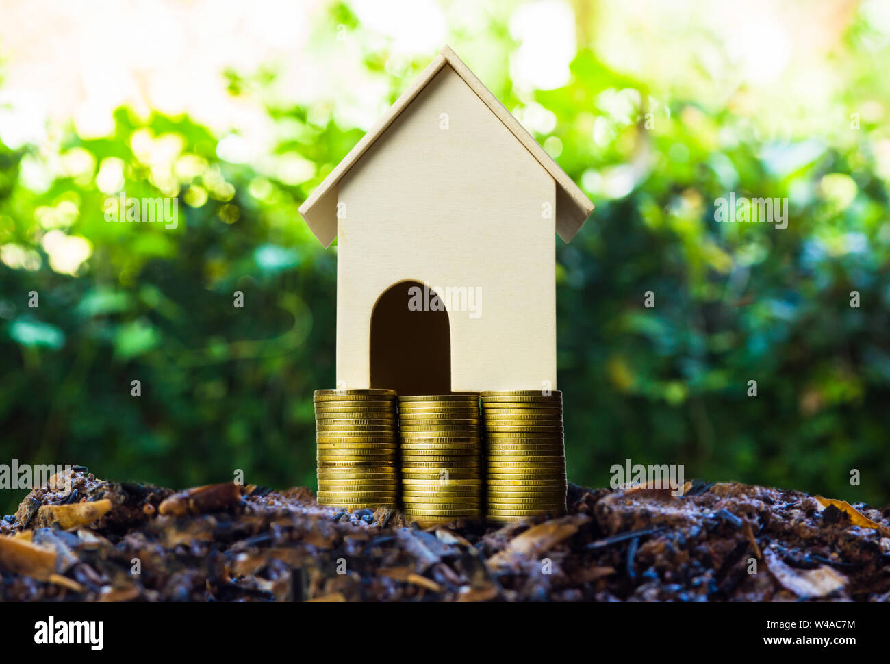 Les concepts d'investissement immobilier. Une petite maison modèle sur pile de pièces et des plantes poussant sur la bonne terre avec la nature. Décrit une longue et durable- Banque D'Images
