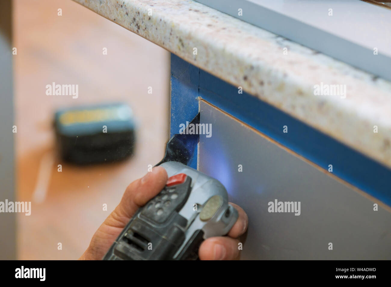 Coupe meubles multi fonctions oscillantes power tool sur l'ossature des armoires de cuisine Banque D'Images