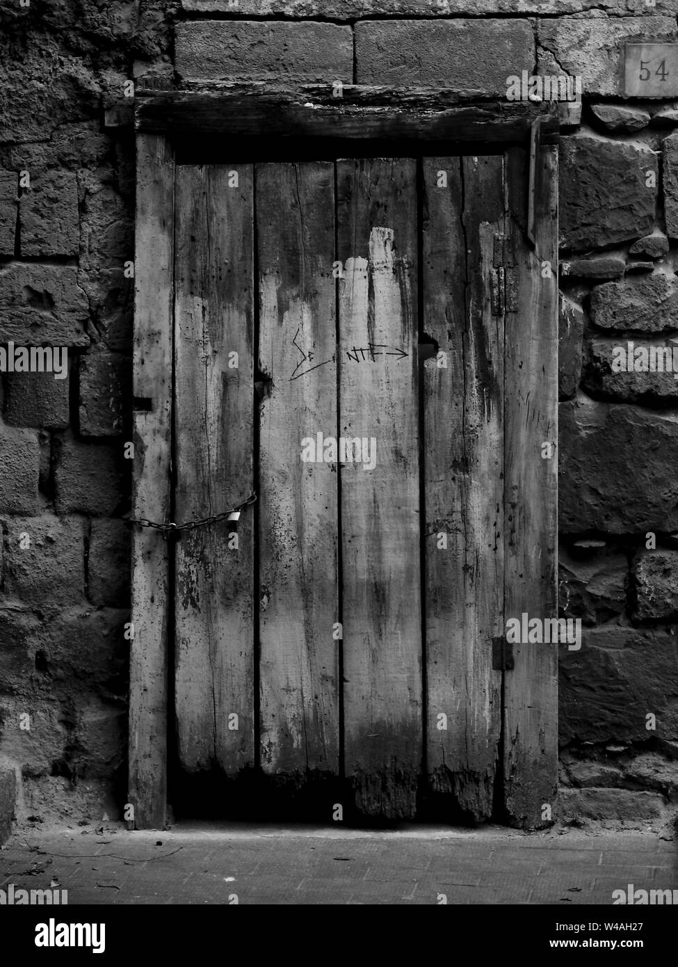 Photo noir et blanc d'une ancienne porte en bois de une maison en pierre Banque D'Images