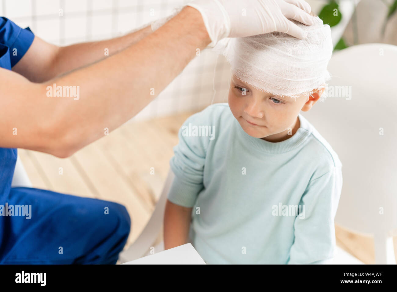 Médecin un garçon avec la tête bandée traumatisme dans la tête et un bandage élastique autour de sa tête Banque D'Images