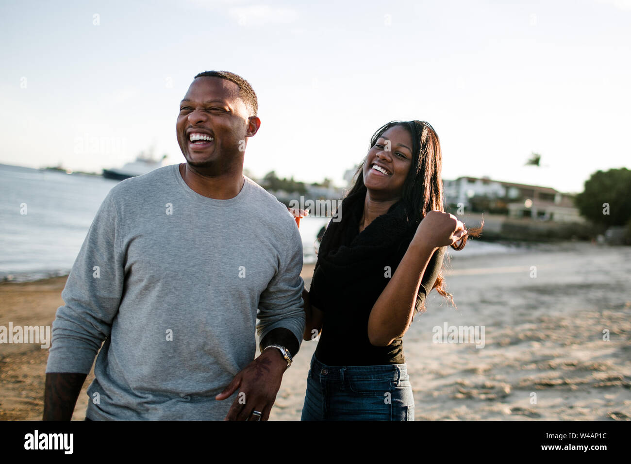 Père et fille rire ensemble sur la plage au coucher du soleil Banque D'Images