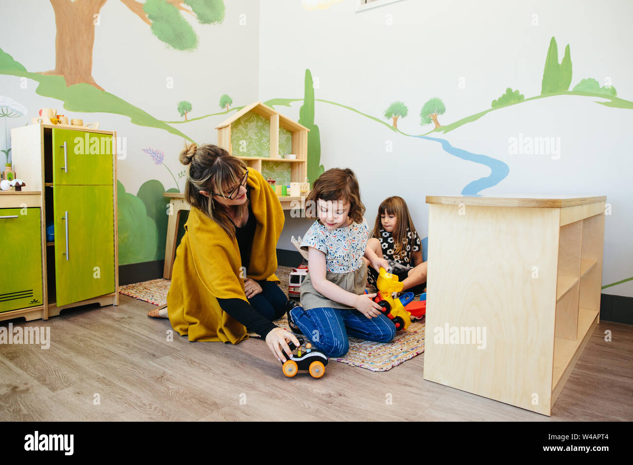 Enseignant assis sur sol pousse une petite voiture montrant un étudiant Banque D'Images