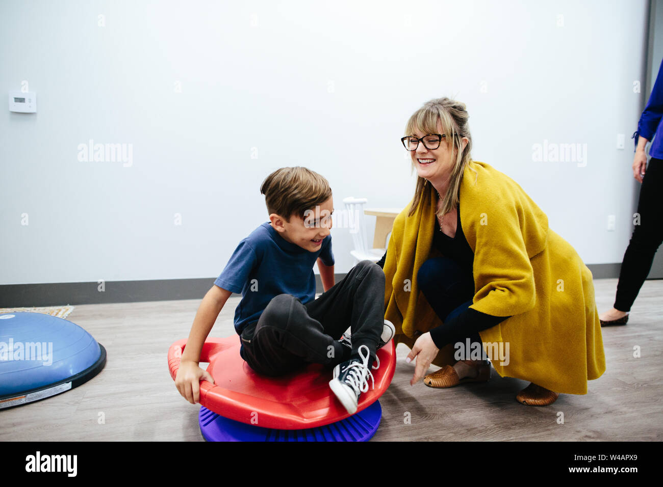 Femme tourne enfant sur un siège tournant sensorielle Banque D'Images