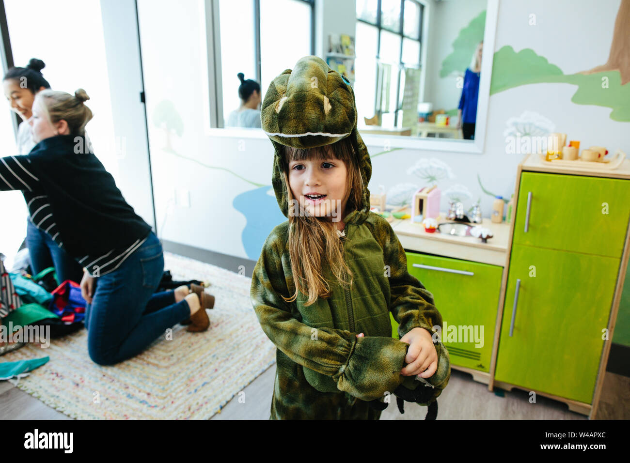 Jeune fille à l'école dans un costume de dinosaure sourit tout en regardant ailleurs Banque D'Images
