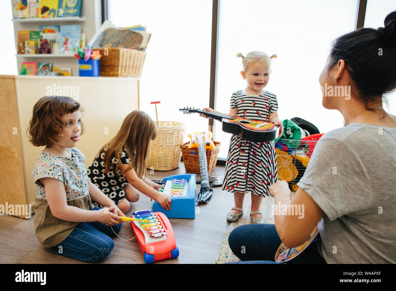 Bébé fille tenant une guitare interagit avec l'enseignant Banque D'Images