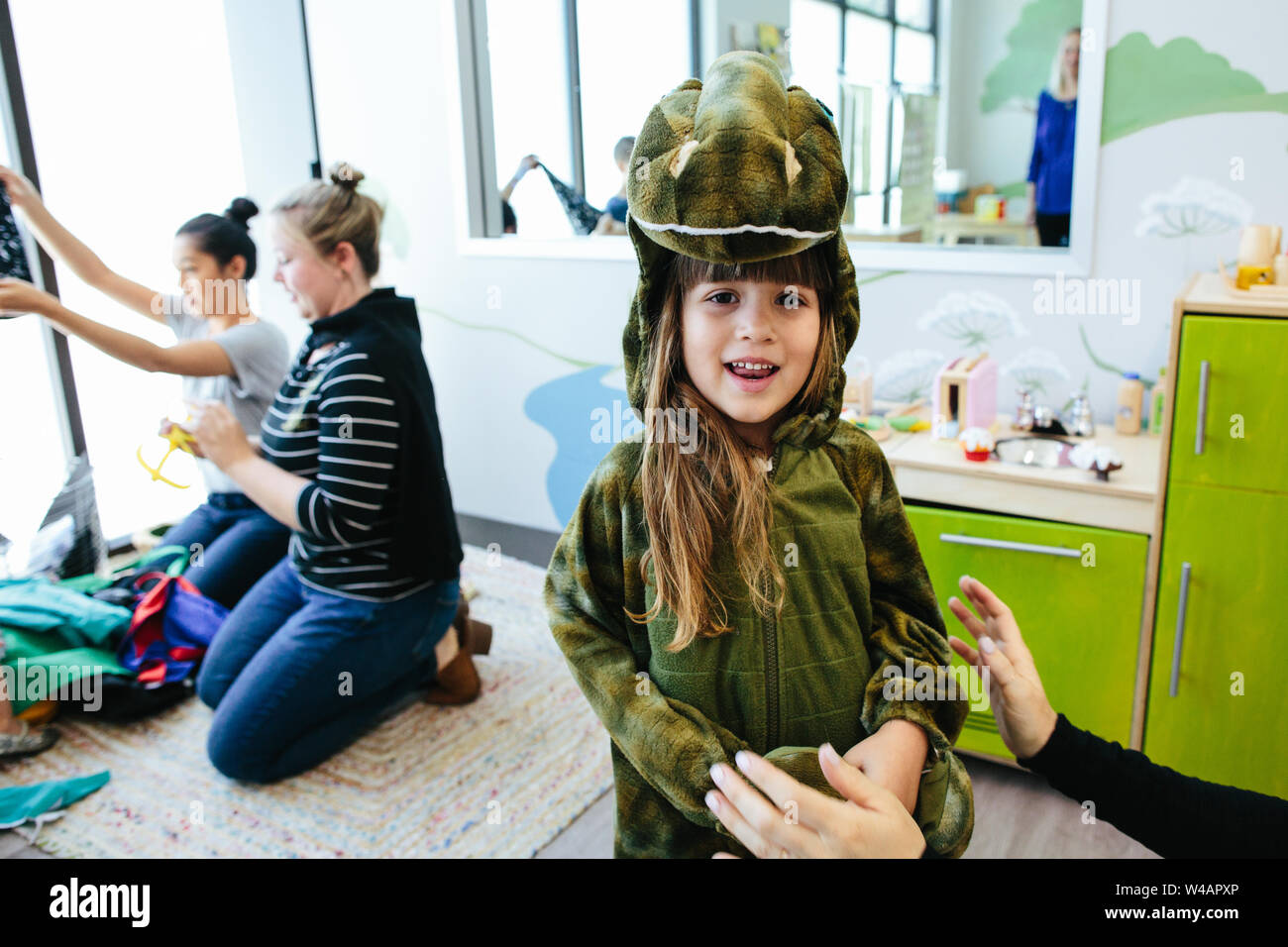 Petite fille a souri à l'appareil photo tout en portant un costume de dinosaure à l'école Banque D'Images