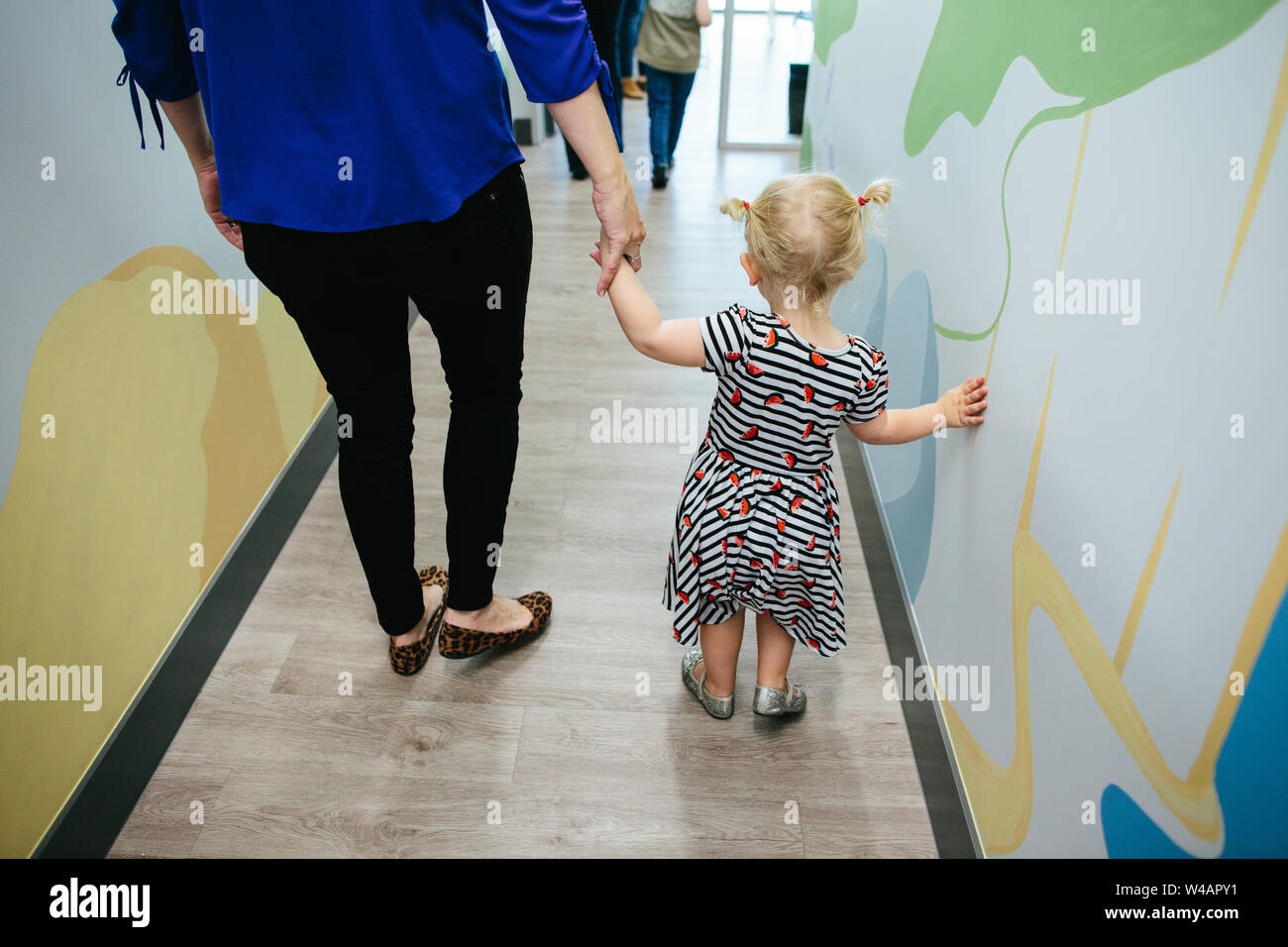 Le dos de bébé fille et femme tenant la main tout en marchant Banque D'Images