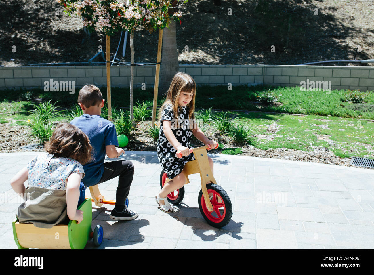 Les enfants à l'extérieur de jouer sur des vélos en bois Banque D'Images