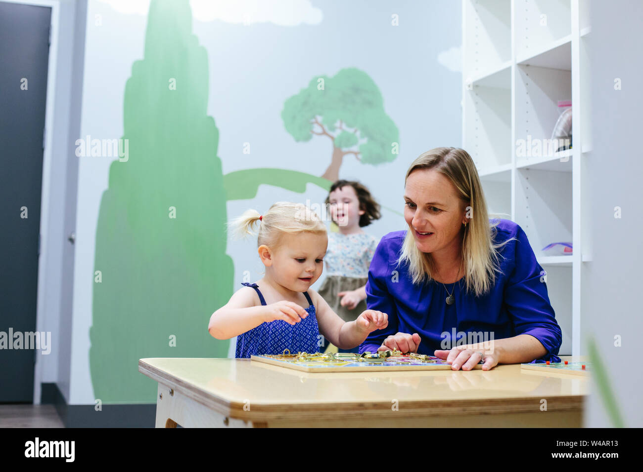 Tout-petit et travailler ensemble sur l'enseignant à table puzzle Banque D'Images