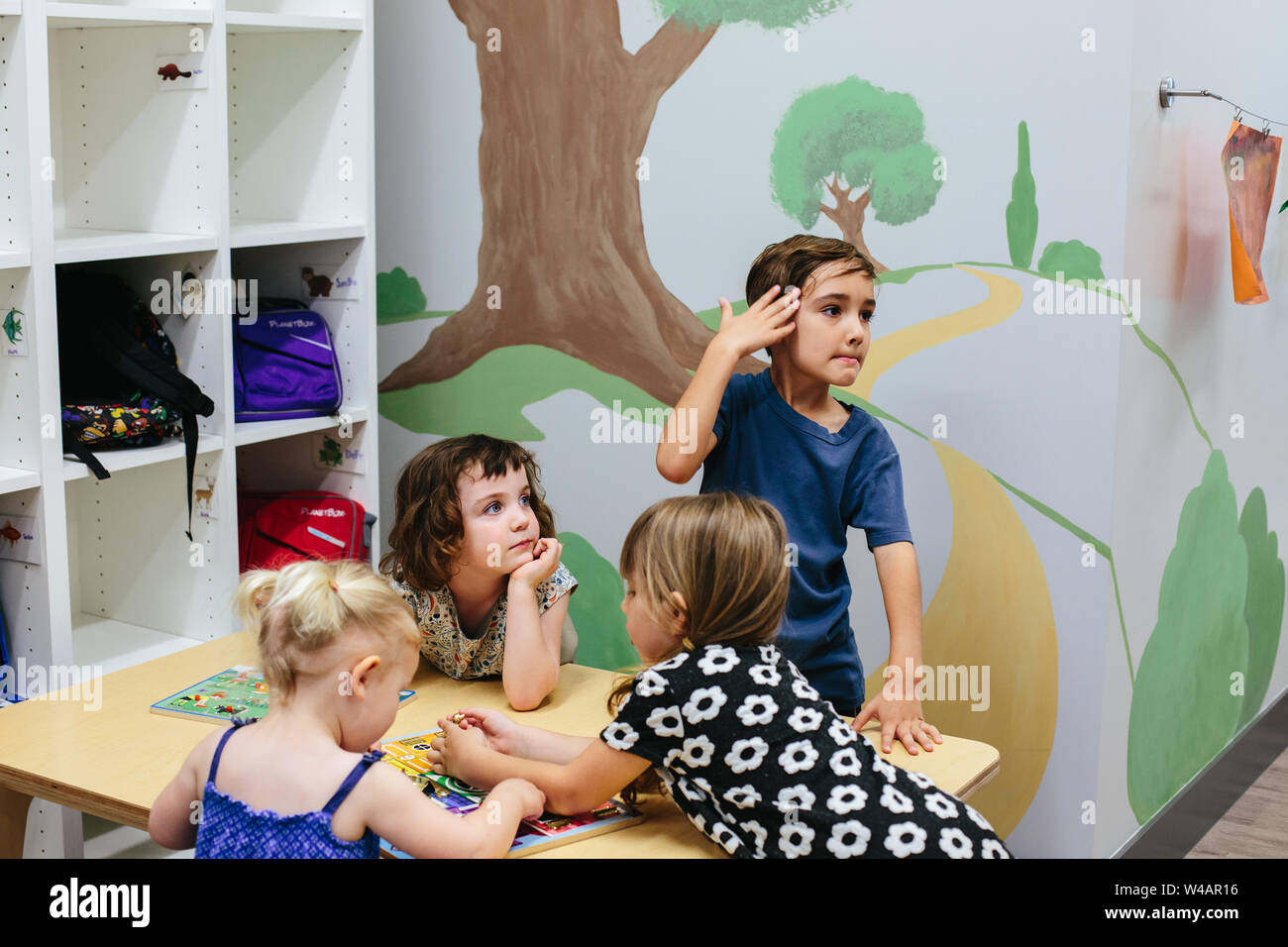 Les enfants à une table dans une école alors que deux regarder vers leur gauche Banque D'Images