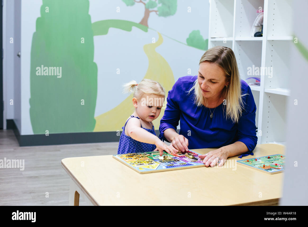 Bébé fille atteint de travailler sur casse-tête avec les enseignants par son côté Banque D'Images