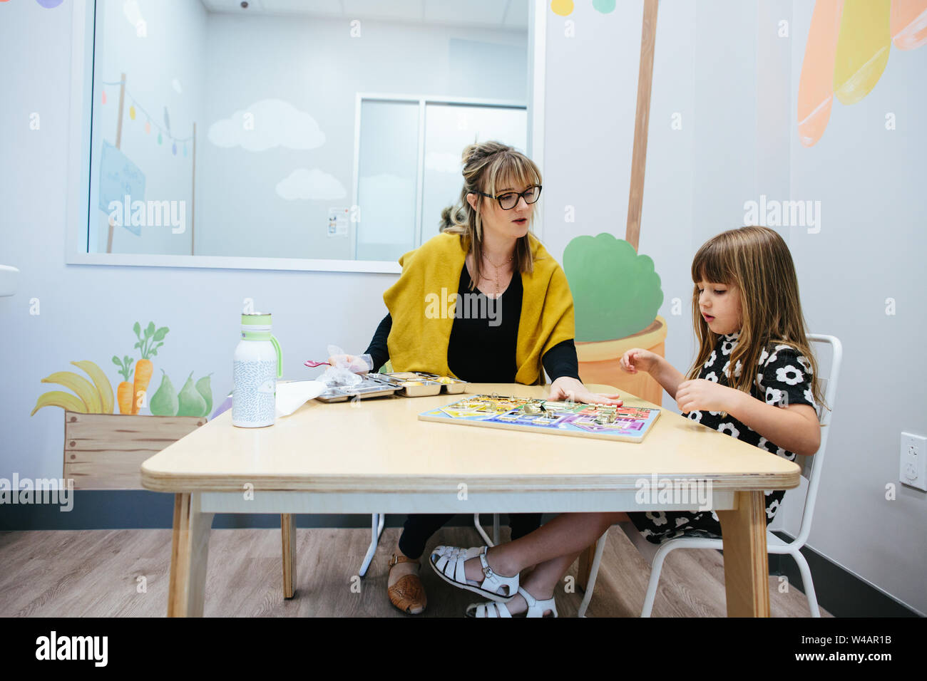 Élève et l'enseignant s'asseoir à une table et de travailler sur un casse-tête Banque D'Images